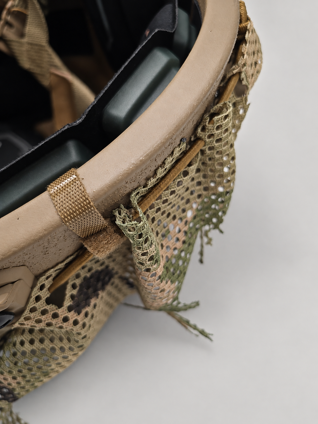 Close-up of the Tatou Armor MultiCam mesh helmet cover on a tan tactical helmet