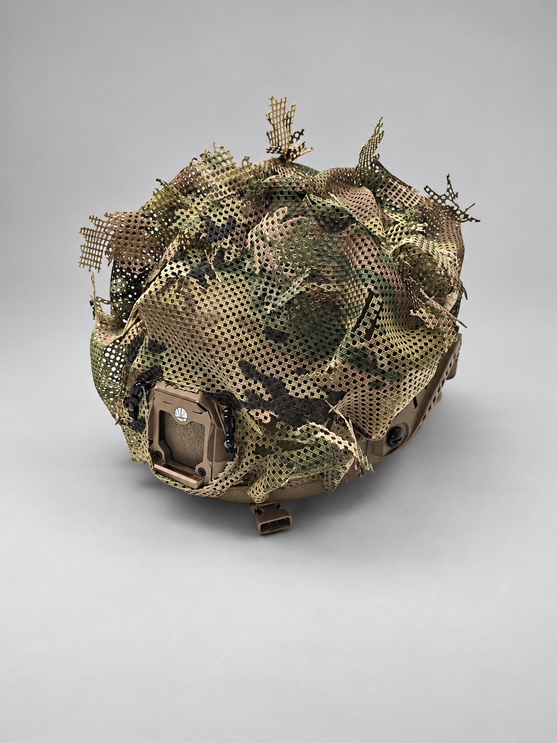 Canadian-made MultiCam mesh helmet cover displayed on a tan tactical helmet against a light grey studio background